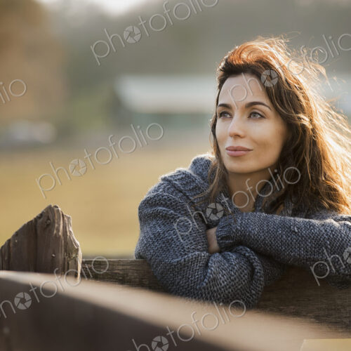 A woman leaning on a fence on an organic farm. A woman leaning on a fence on an organic farm.
