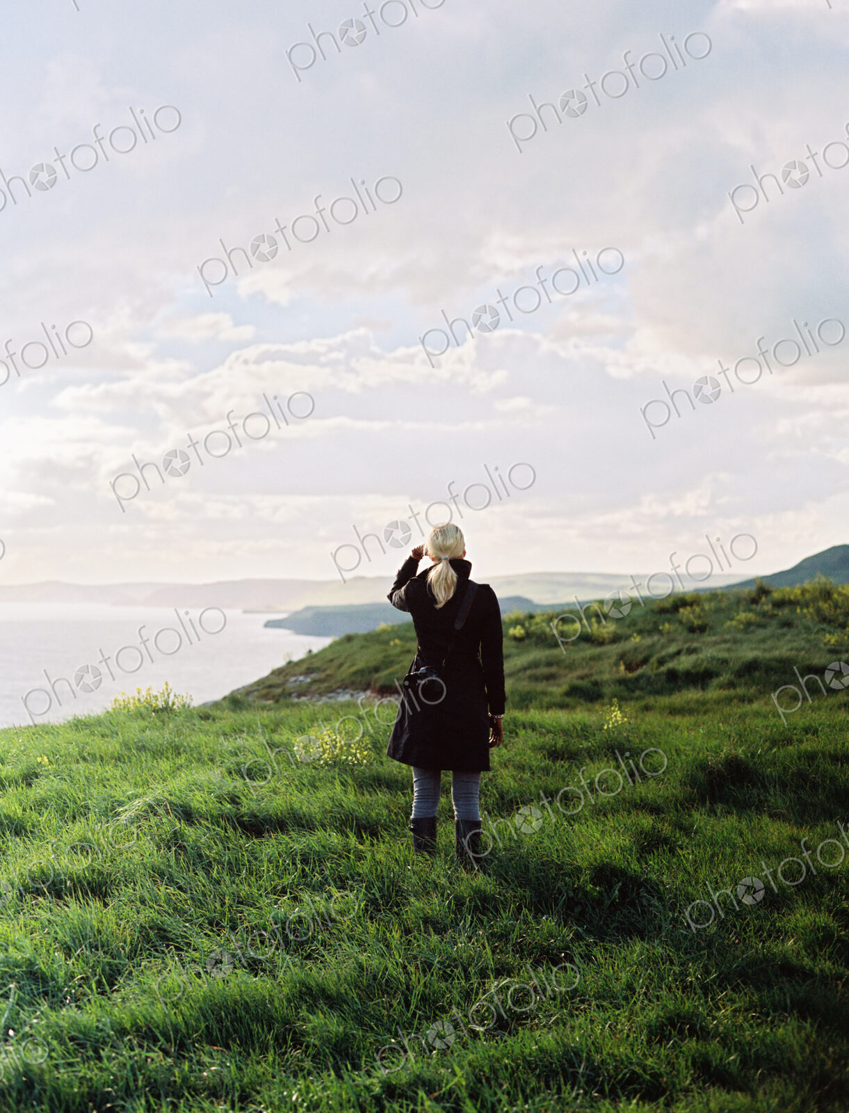 A woman looking along the coastline, inlets and cliffs.