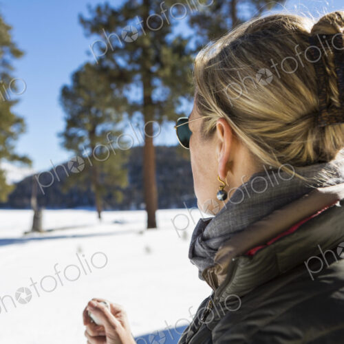 A woman looking at a beautiful snow landscape with pine trees.