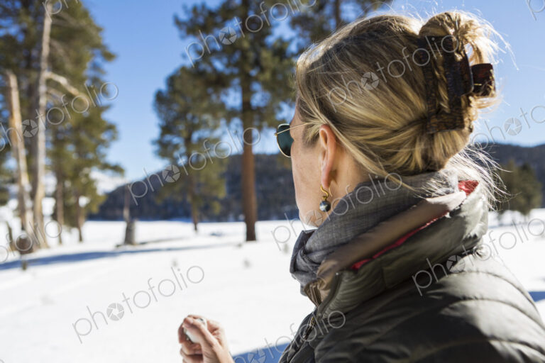 A woman looking at a beautiful snow landscape with pine trees.