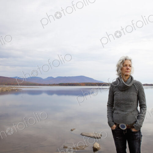 A woman looking out over the water on the shores of a calm lake. A woman looking out over the water on the shores of a calm lake.