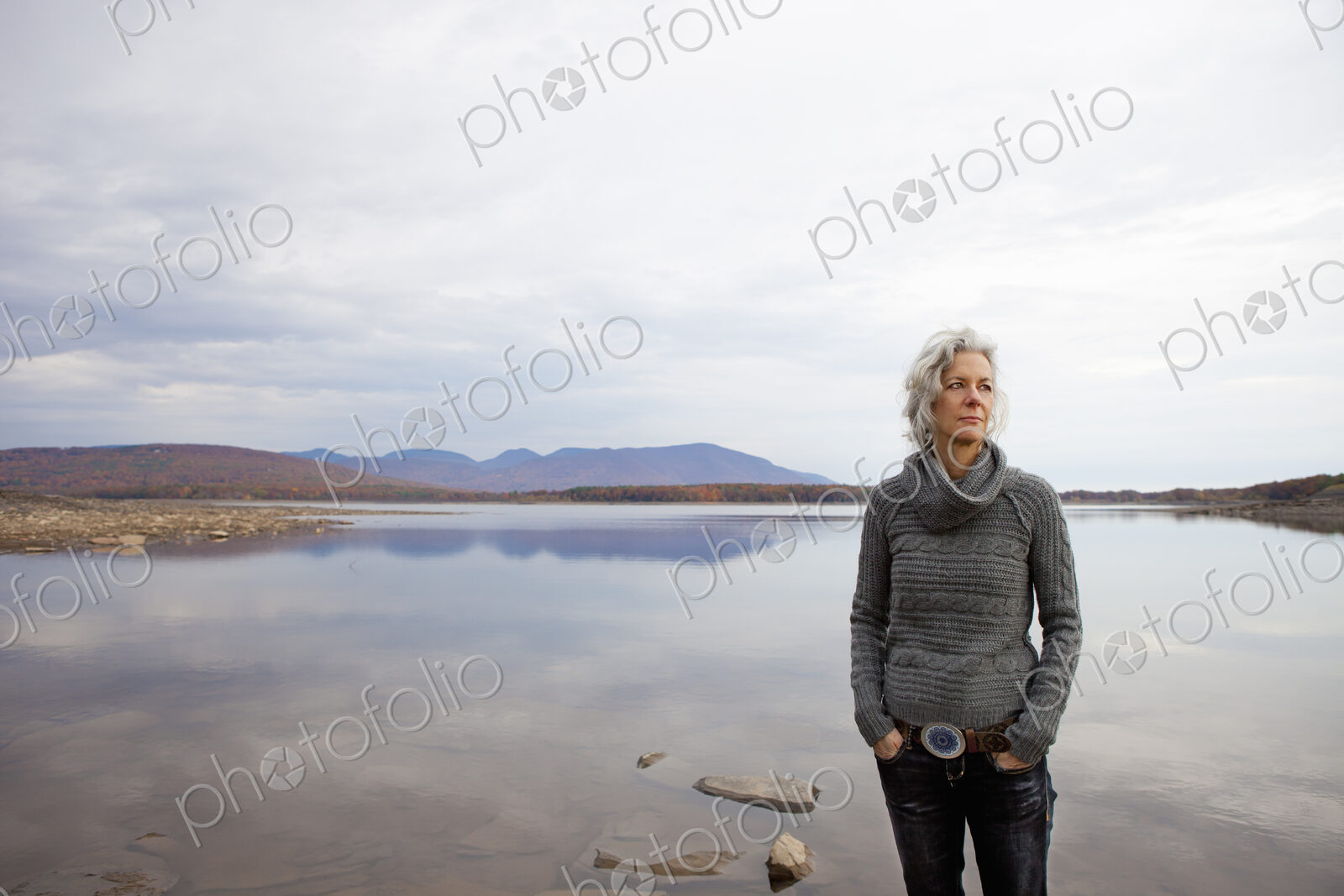 A woman looking out over the water on the shores of a calm lake.
