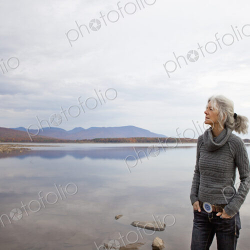 A woman looking out over the water on the shores of a calm lake. A woman looking out over the water on the shores of a calm lake.
