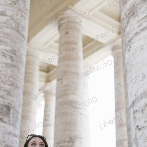 A woman looking up at the tall pillars and arches of a historic building in Rome.