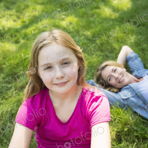 A woman lying on the grass relaxing and a young girl looking at the camera. A woman lying on the grass relaxing and a young girl looking at the camera.