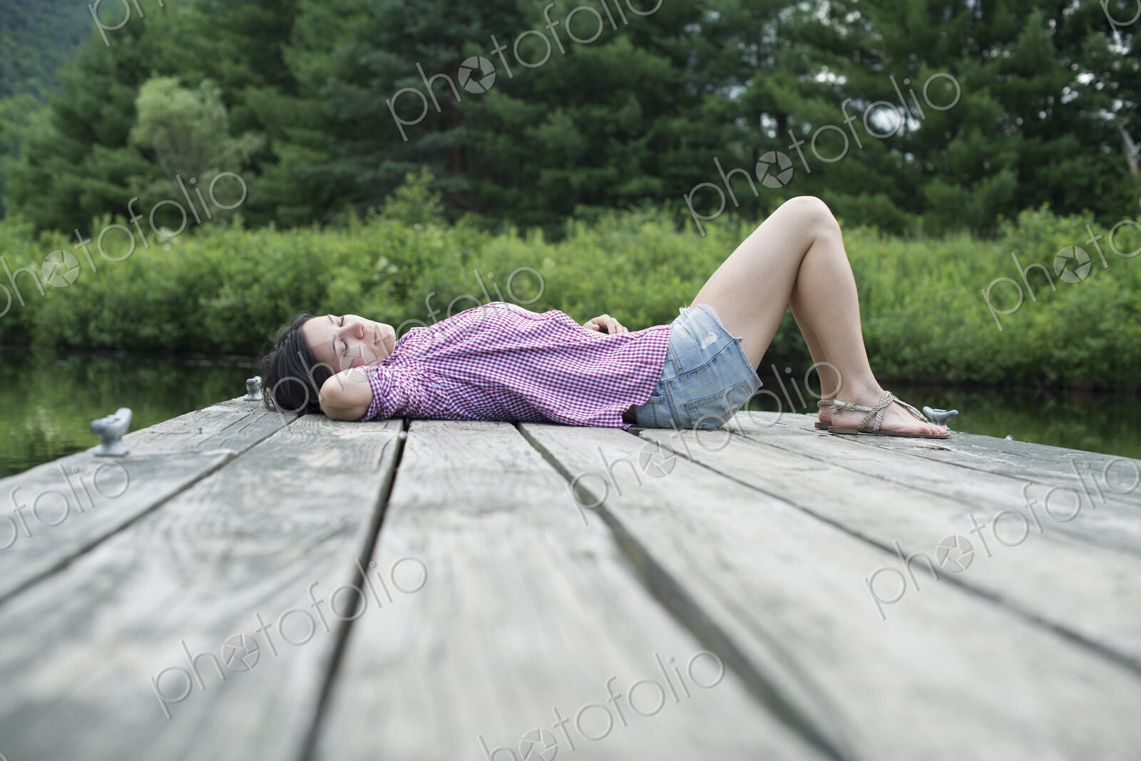A woman lying on the jetty by a lake in summer