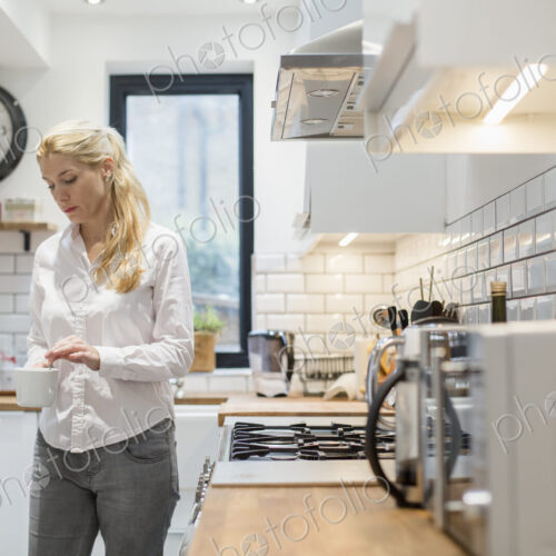 A woman making a cup of tea in a modern kitchen. A woman making a cup of tea in a modern kitchen.