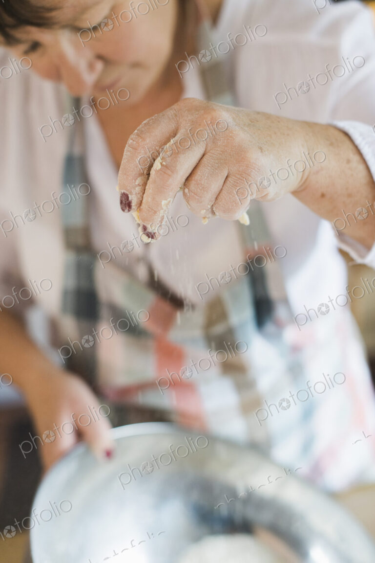 A woman measuring and sifting white flour, making a crumble topping. Home baking.