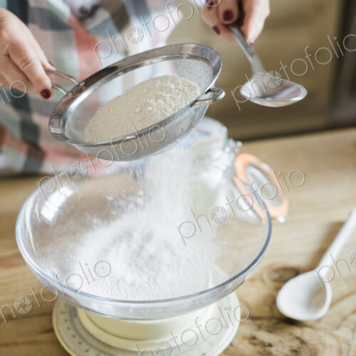 A woman measuring and sifting white flour. Home baking.