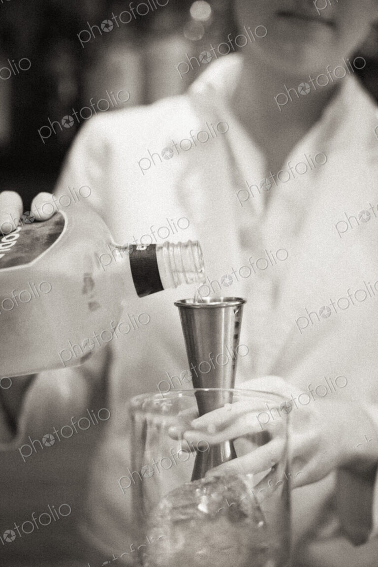 A woman mixing a cocktail, a mixologist at work.