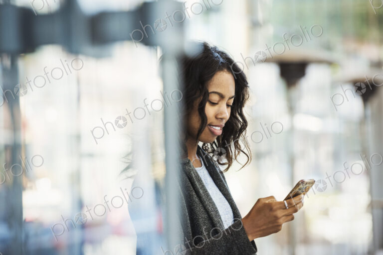 A woman on a city street, checking her mobile phone.