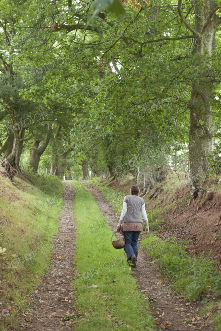 A woman on a country lane, a forager carrying a basket.