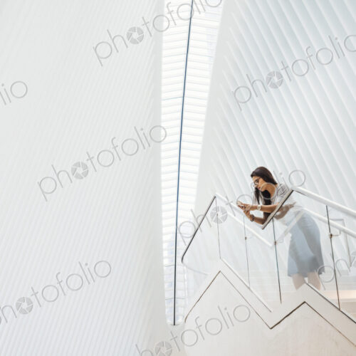 A woman on the stairs leaning on a railing in a modern building A woman on the stairs leaning on a railing in a modern building