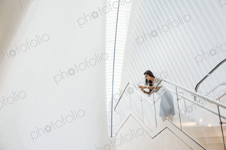 A woman on the stairs leaning on a railing in a modern building