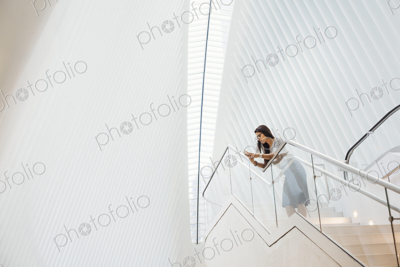 A woman on the stairs leaning on a railing in a modern building