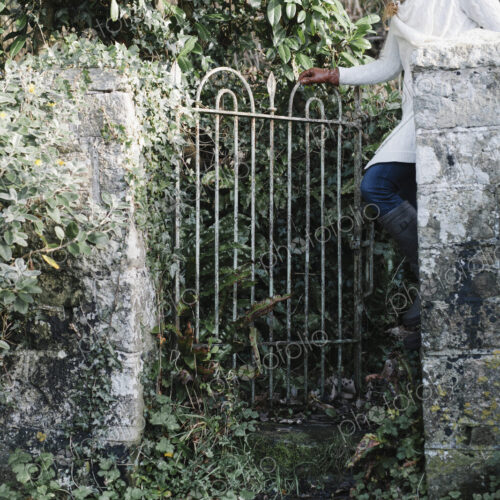 A woman opening a garden gate.