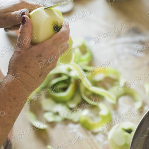 A woman peeling a green skinned apple. A woman peeling a green skinned apple.