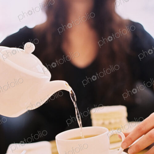 A woman pouring a cup of tea from a teapot A woman pouring a cup of tea from a teapot