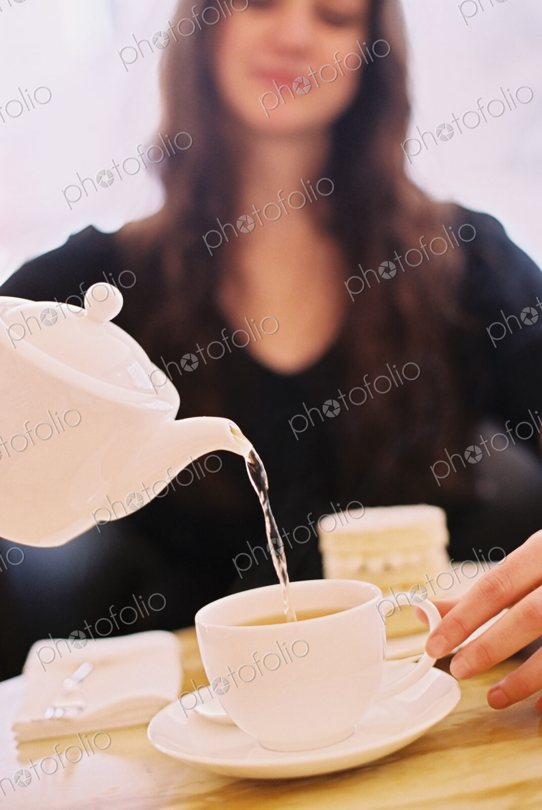 A woman pouring a cup of tea from a teapot