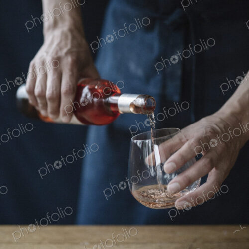 A woman pouring a drink from a bottle.