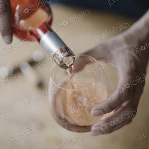 A woman pouring a drink from a bottle of wine.