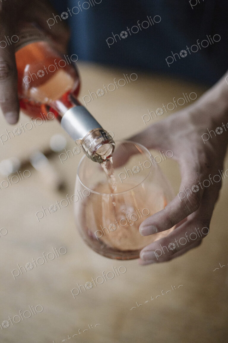 A woman pouring a drink from a bottle of wine.