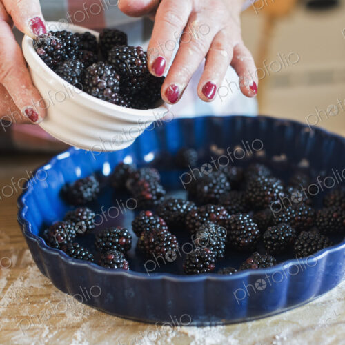 A woman pouring fresh blackberries into a dish.