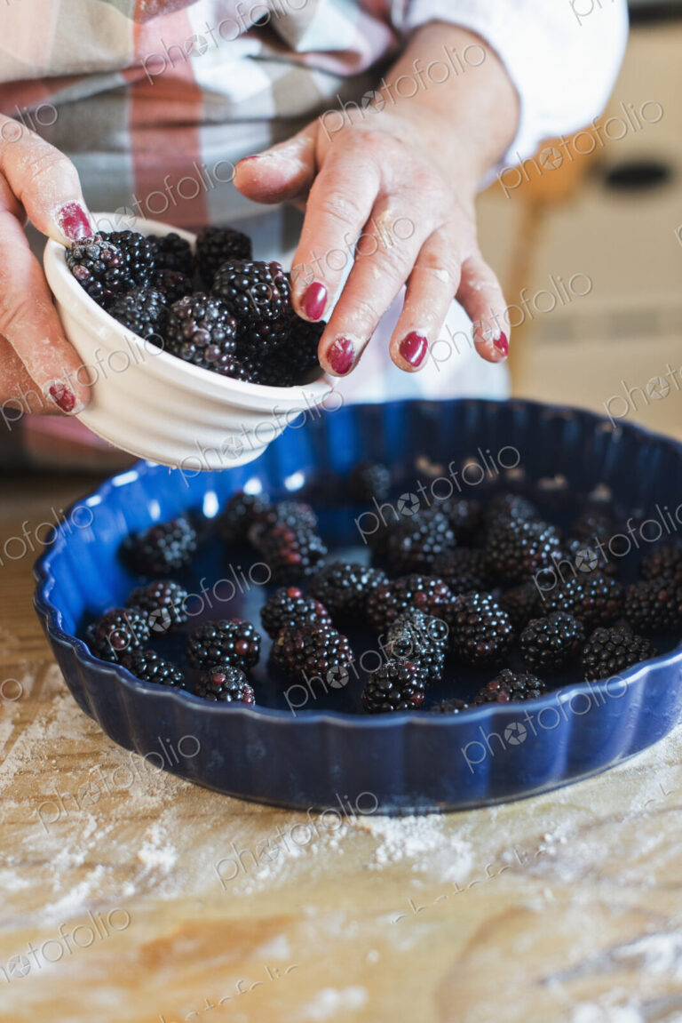 A woman pouring fresh blackberries into a dish.
