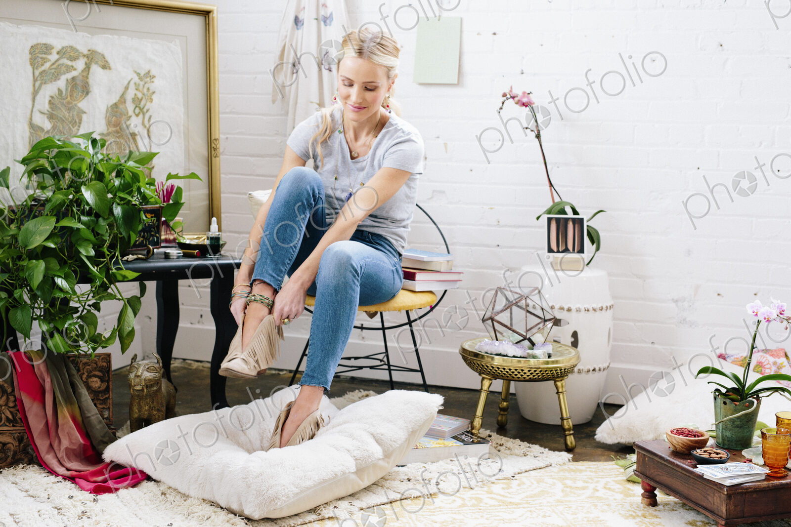 A woman putting on suede boots.
