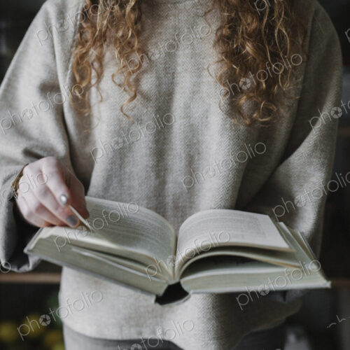 A woman reading from a recipe book in a kitchen.