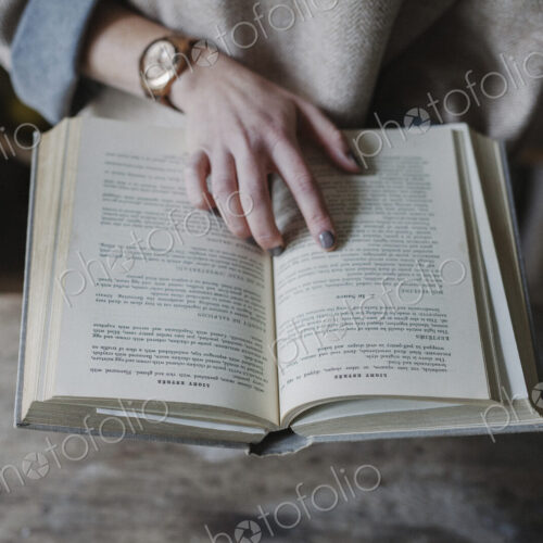 A woman reading from a recipe book in a kitchen.
