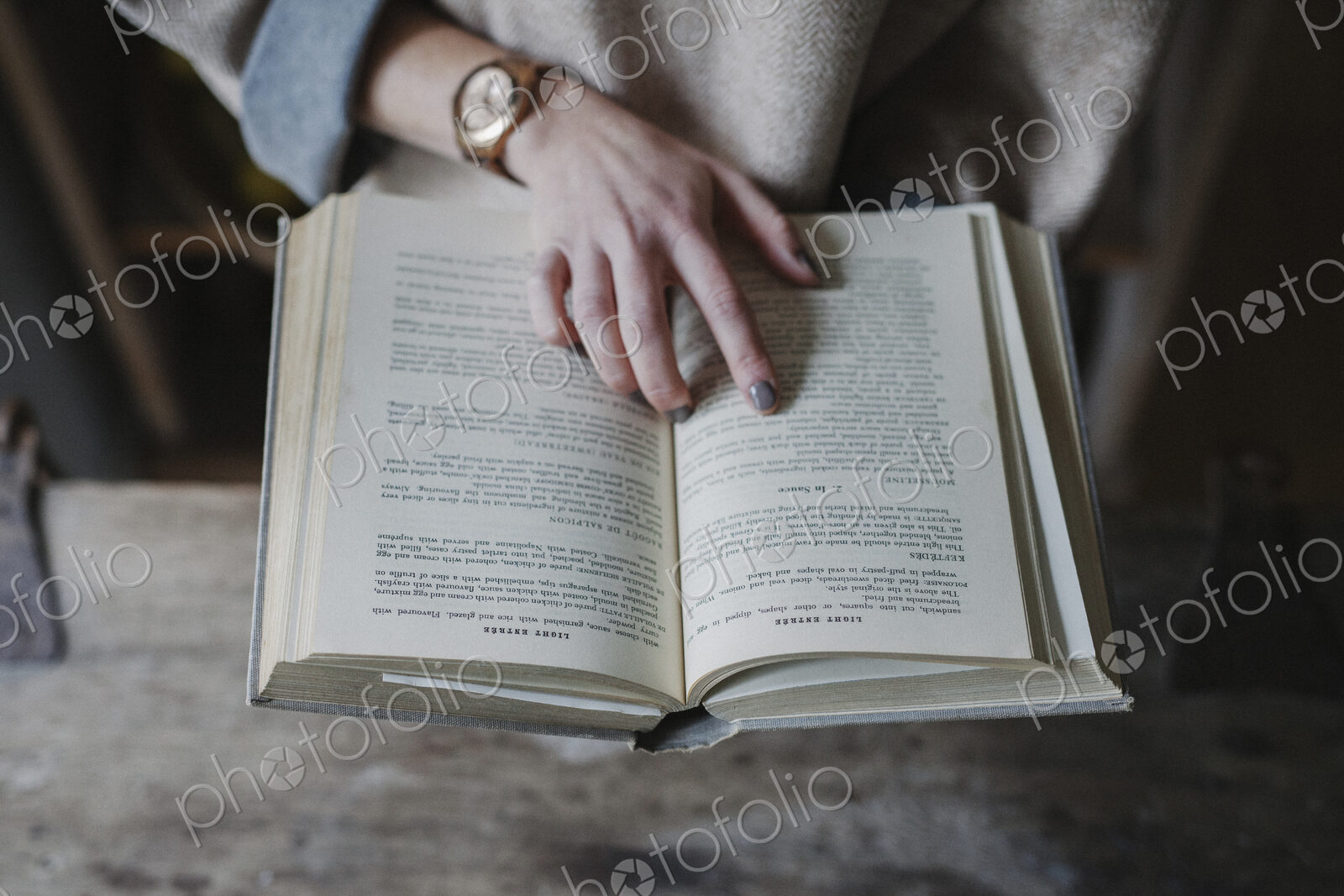 A woman reading from a recipe book in a kitchen.
