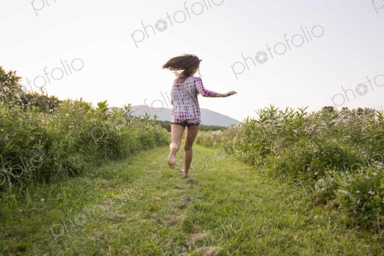 A woman running along a path in a meadow.