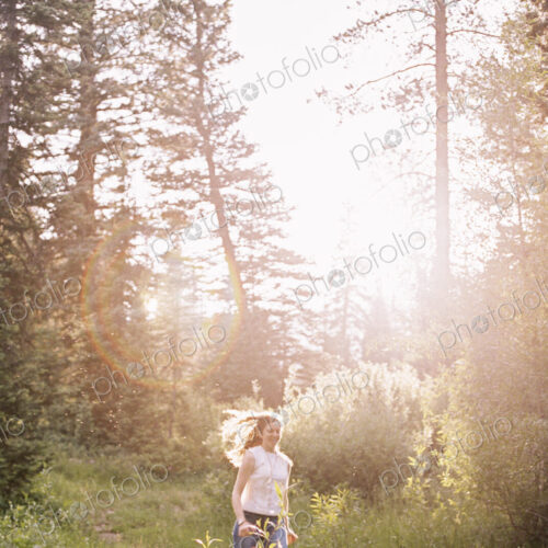 A woman running through a sunlit forest. A woman running through a sunlit forest.