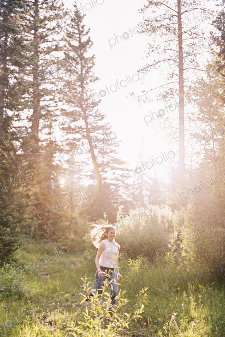 A woman running through a sunlit forest.