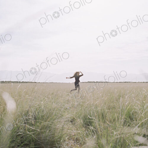 A woman running through long grass, view from a distance. A woman running through long grass, view from a distance.