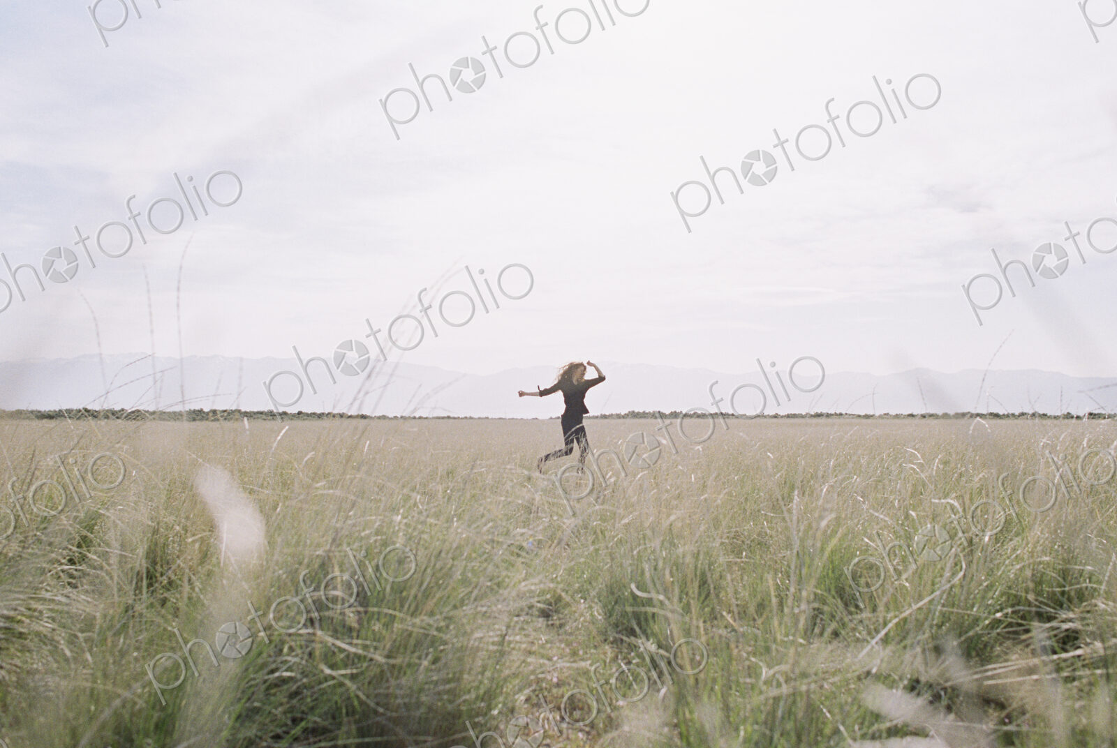 A woman running through long grass, view from a distance.