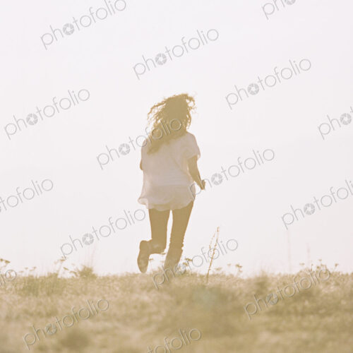 A woman running with her long hair fanning out behind her.