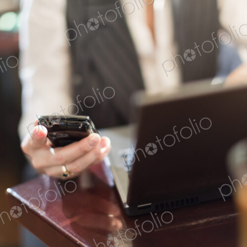 A woman seated at a desk holding a smart phone, with a laptop computer. A woman seated at a desk holding a smart phone, with a laptop computer.