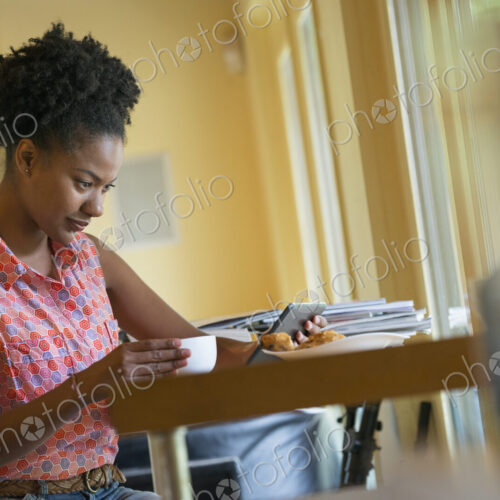 A woman seated having a cup of coffee. Holding an ebook or a digital tablet. A woman seated having a cup of coffee. Holding an ebook or a digital tablet.