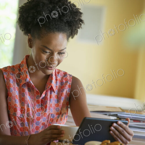 A woman seated having a cup of coffee. Holding an ebook or a digital tablet. A woman seated having a cup of coffee. Holding an ebook or a digital tablet.