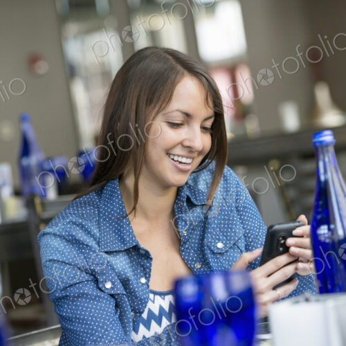A woman seated in a cafe using a smart phone. A woman seated in a cafe using a smart phone.
