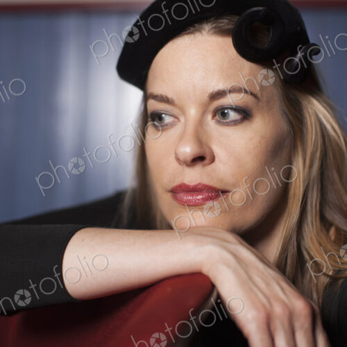 A woman seated in a theatre, wearing an elegant evening hat, and a black top. Resting… A woman seated in a theatre, wearing an elegant evening hat, and a black top. Resting…