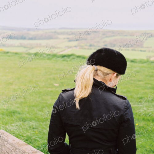 A woman seated on a bench looking over the landscape to the sea. A woman seated on a bench looking over the landscape to the sea.