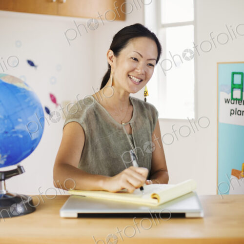 A woman sitting at a desk in a classroom.