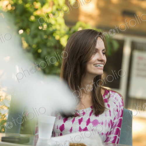 A woman sitting at a table in a garden. A woman sitting at a table in a garden.