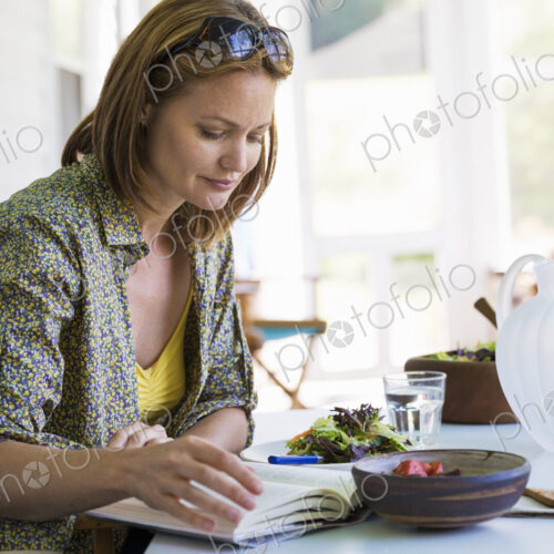 A woman sitting at a table reading a book. A woman sitting at a table reading a book.