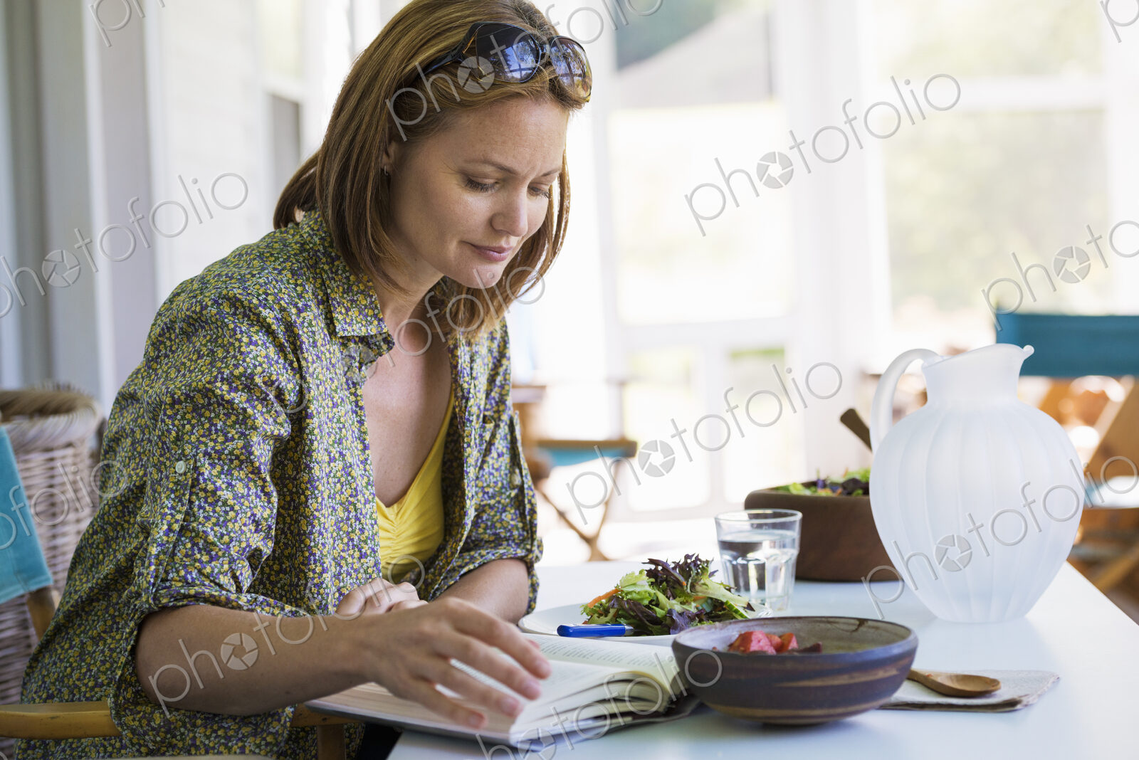 A woman sitting at a table reading a book.