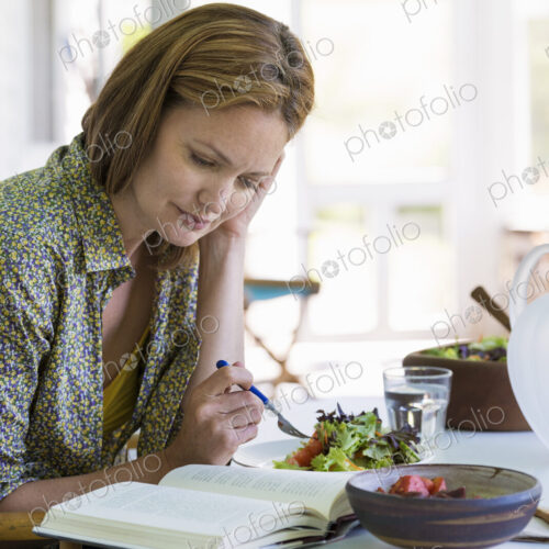 A woman sitting at a table reading a book. A woman sitting at a table reading a book.