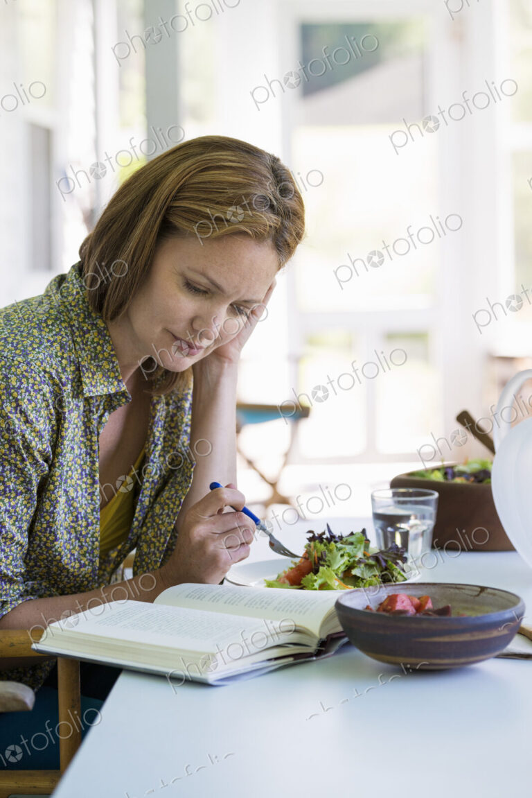 A woman sitting at a table reading a book.